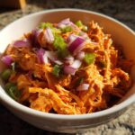 A bowl of 10 Minute Buffalo Chicken Salad topped with chopped red onion and green onions.