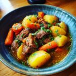 Close-up van een kom met heerlijke Beef Stew, vol met mals rundvlees, aardappelen en wortelen, gegarneerd met peterselie.