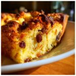 Een close-up van een stuk broodpudding met rozijnen, met een goudbruine korst en zachte binnenkant.