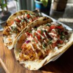 Two Delicious Grilled Fish Tacos topped with pico de gallo, shredded lettuce, and spicy mayo.