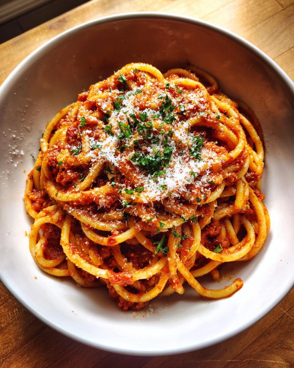 A close-up of a bowl of spaghetti with a hearty tomato meat sauce, topped with grated Parmesan cheese and fresh parsley.