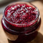 Close-up of a glass jar filled with glistening, homemade Delightful Blackberry Jam.