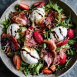 A close-up of a Delightful Prosciutto Strawberry Burrata Salad with fresh strawberries, creamy burrata, and prosciutto.