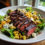 A close-up of a Flavorful Balsamic Steak Gorgonzola Salad with grilled corn and crumbled gorgonzola cheese.