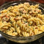 Close-up of a bowl of flavorful and zesty pasta salad with fusilli pasta, chicken, and herbs.