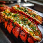 Close-up of perfectly Grilled Lobster Tails topped with glistening Garlic Herb Butter and fresh parsley.