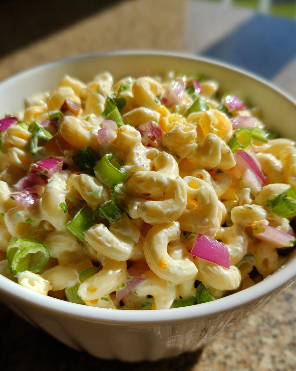 Close-up of Guy Fieri's Macaroni Salad, a creamy pasta salad with red onion, green onions, and other colorful ingredients.