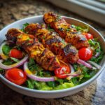 A bowl of Irresistible BBQ Chicken Skewer Salad with grilled chicken, cherry tomatoes, red onion, and lettuce.