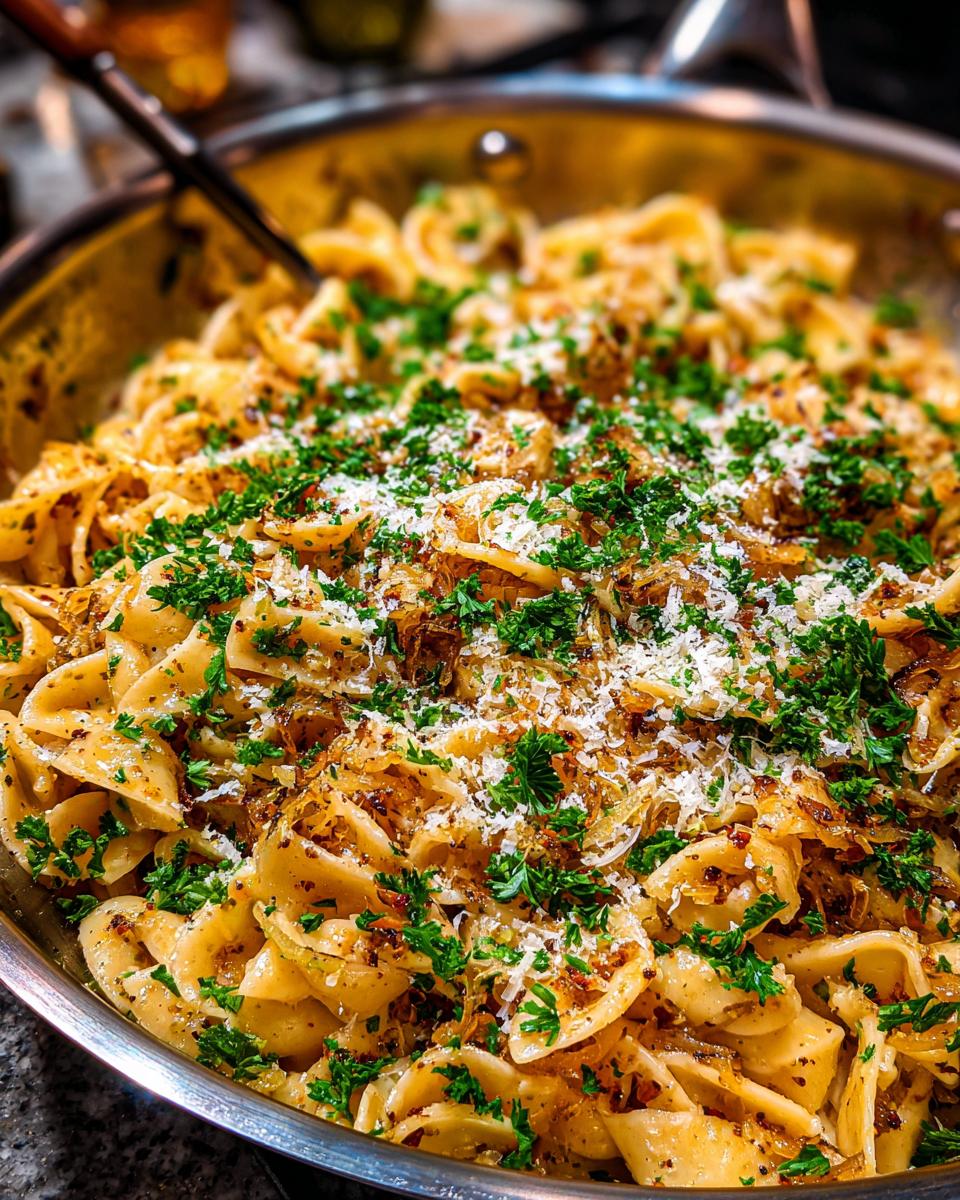 A close-up of Irresistible Caramelized Onion Pasta, generously topped with fresh parsley and grated Parmesan cheese.