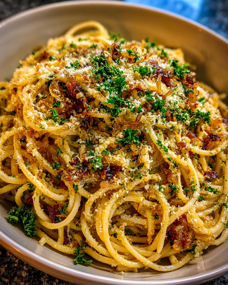 A close-up of a bowl of Irresistible Caramelized Onion Pasta, topped with parsley and breadcrumbs.