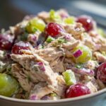 Close-up of Irresistible Chicken Salad Recipe With Grapes, featuring shredded chicken, red and green grapes, and red onion.