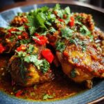 A close-up of Irresistible Curry Chicken in a rich, savory sauce, garnished with fresh cilantro and red chili pieces.