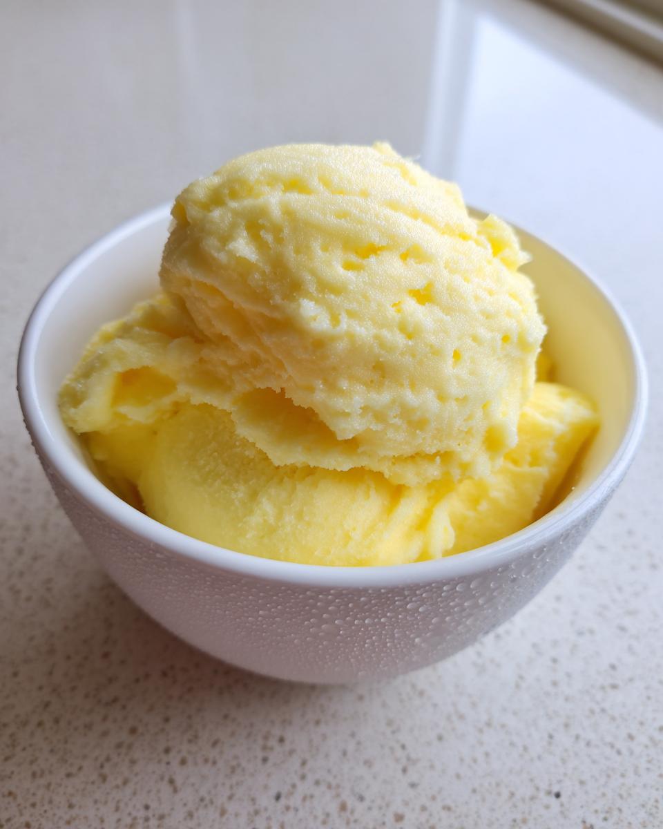 Close-up of a white bowl filled with scoops of creamy, yellow pineapple Dole Whip.