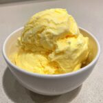 A white bowl filled with creamy yellow scoops of an irresistible Dole Whip recipe, perfect for a tropical treat.