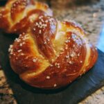 Close-up of two irresistible homemade soft pretzels, brushed with egg wash and sprinkled with coarse salt.