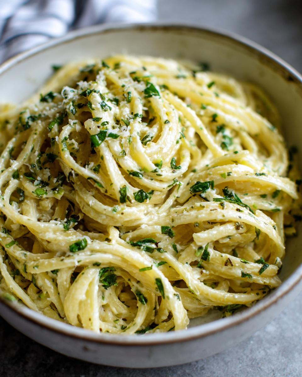 A close-up of Irresistible Lemon Ricotta Pasta in a bowl, coated in creamy sauce and sprinkled with fresh herbs.