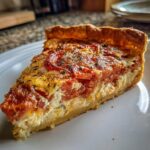 A delicious slice of Irresistible Tomato Pie, showcasing layers of fresh tomatoes and creamy filling on a golden crust.