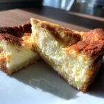 Twee heerlijke stukken Keto Sugar Cookie Cheesecake Bars op een wit bord, met een romige vulling en goudbruine korst.