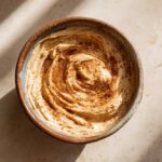 Close-up van een kom met luchtige honing kaneel spread, bestrooid met kaneel.