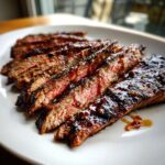 Close-up of sliced Mouthwatering Grilled Flank Steak With Balsamic Twist, glistening with sauce on a white plate.