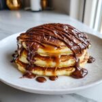 Stapel heerlijke pancakes met rijkelijk dulce de leche en chocoladesaus.