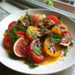 A refreshing heirloom tomato salad with sliced figs, fresh basil, and a drizzle of balsamic glaze.
