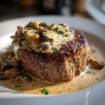 Close-up van romige Boursin Filet Mignon met champignons en peterselie op een wit bord.