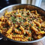Close-up of a pan filled with Savory Beef and Rotini in Garlic Parmesan Sauce, garnished with fresh parsley.