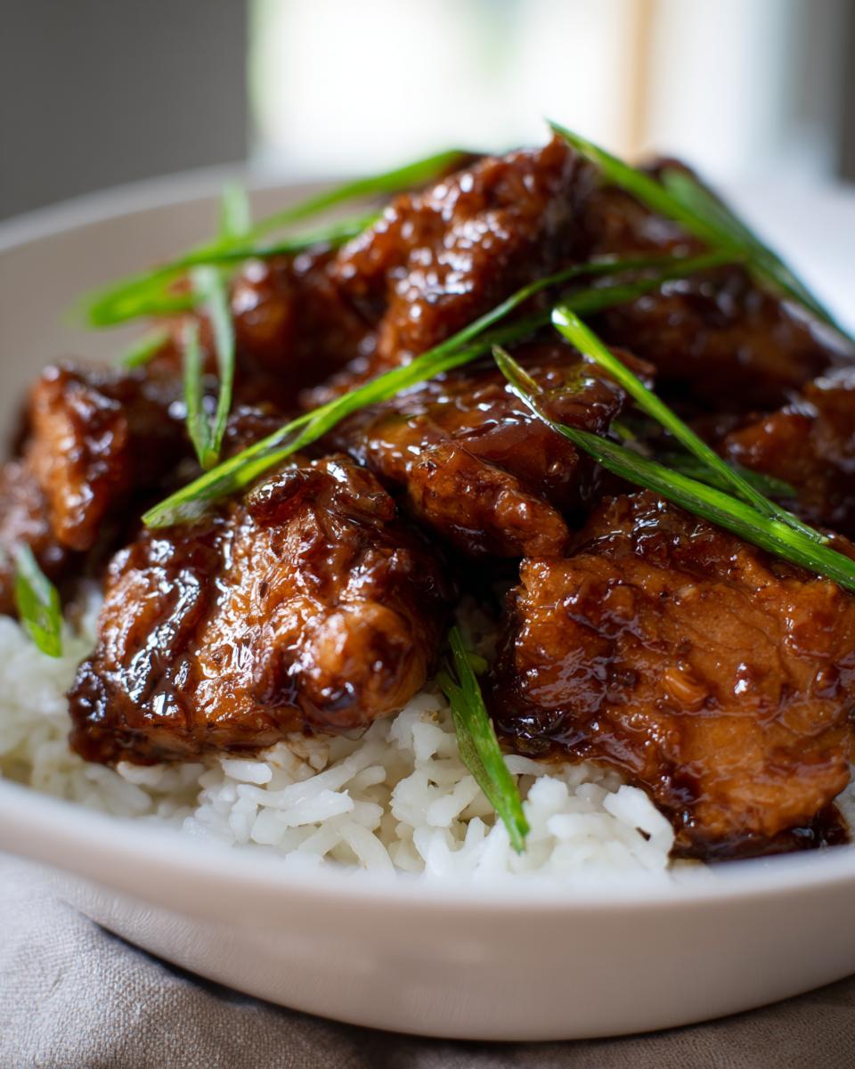 Close-up van heerlijke slow cooker bourbon kip geserveerd op witte rijst en gegarneerd met lente-ui.