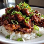 Gekarameliseerde stukjes kip in een rijke saus, geserveerd op witte rijst en gegarneerd met lente-ui. De beste Slow Cooker Bourbon Kip.