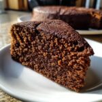 Een close-up van een heerlijk stuk Super Vochtige Peperkoek Cake op een wit bord.