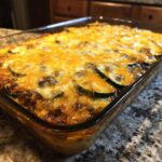 Een Tasty Mexican Zucchini Casserole met gesmolten kaas, vers uit de oven in een glazen schaal.