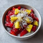Close-up of a Tropical Strawberry Coconut Chia Bowl Delight topped with fresh strawberries, pineapple chunks, shredded coconut, and chia seeds.