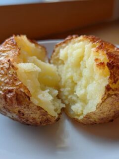 A perfectly cooked Air Fryer Baked Potatoes, split open to show the fluffy interior and crispy skin.