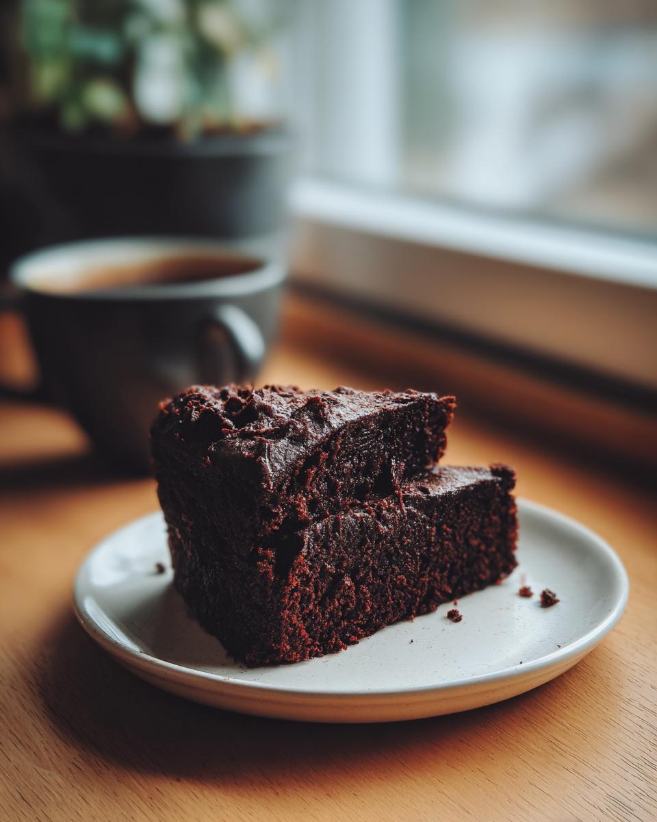 Two stacked slices of rich, moist Black Magic Chocolate Cake on a small white plate.