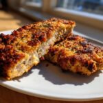 Two pieces of crispy Breaded Baked Pork Chops, cut to show the juicy interior and golden crust.