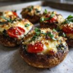Close-up of freshly baked Caprese Stuffed Mushrooms topped with melted mozzarella, tomato, and fresh basil.