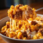A spoonful of cheesy ground beef macaroni casserole, with melted cheese stretching.