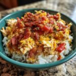 A close-up of a bowl filled with white rice topped with shredded chicken, melted cheese, and crispy bacon bits. This is the Irresistible Crockpot Crack Chicken and Rice Recipe.