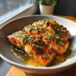 Three perfectly cooked fillets of Irresistible Garlic Butter Salmon, glistening with butter sauce and topped with fresh parsley.