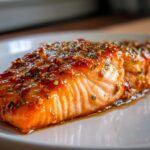 Close-up of a glistening fillet of Irresistible Honey Garlic Salmon Recipe, glazed and topped with herbs.