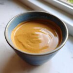 A close-up of a bowl filled with Irresistible Thai Peanut Sauce, showing its creamy texture and rich color.