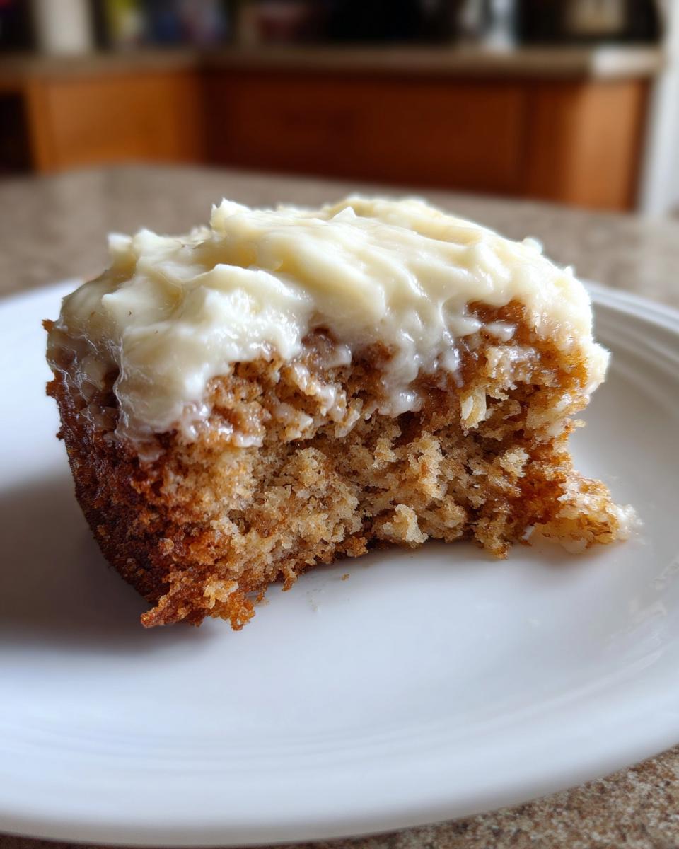 Close-up of a moist slice of Banana Cake With Cream Cheese Frosting on a white plate, showing the crumb texture.