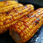 Close-up of perfectly cooked air fryer corn on the cob, seasoned with spices and slightly charred.