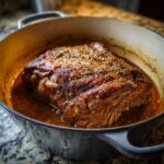 A juicy, seasoned Traeger Mississippi Pot Roast cooking in a Dutch oven with rich gravy.