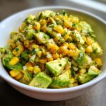 A bowl of Zesty Avocado Corn Salad, a Memorial Day Favorite Recipe, with fresh avocado, corn, and herbs.
