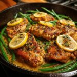Close-up of Zesty Lemon Garlic Butter Chicken and Green Beans Skillet in a cast iron pan, garnished with lemon slices and herbs.