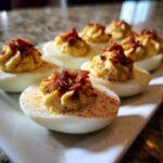 Een close-up van gevulde eieren met een romige vulling, getopt met krokant spek, als Bacon En Olijven Gevulde Eieren.