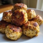 Close-up van een stapel goudbruin gebakken Cashew Chicken Meatballs op een wit bord.