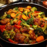 Close-up van een glanzende Chicken And Vegetables Skillet met broccoli, wortel en paprika in een koekenpan.